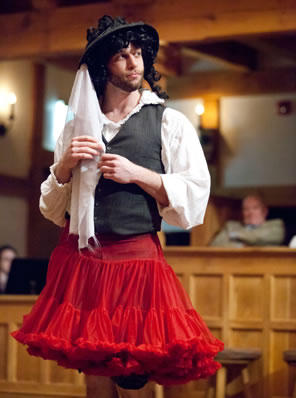 The character of Follywit in a red dress over his regular outfit and a hat with a veil